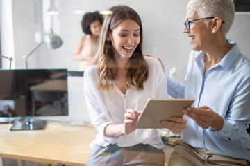 Two business women, laughing and smiling in conversation